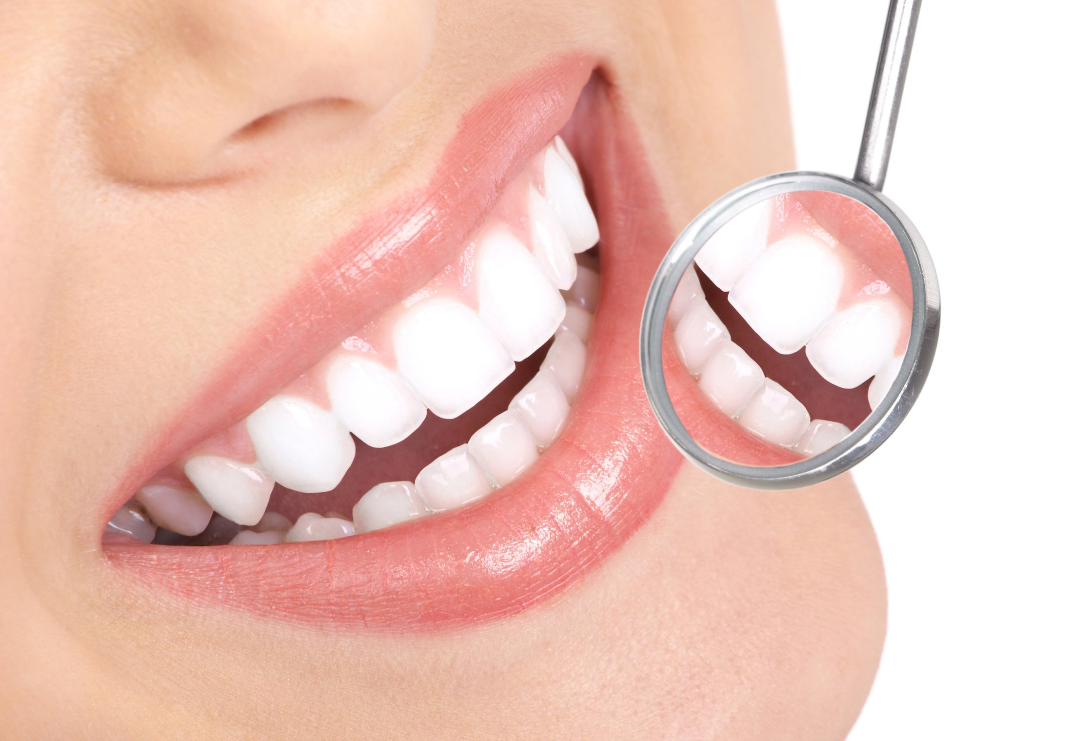 dental mirror showing the reflection of a smiling set of teeth
